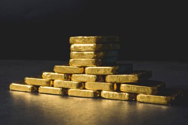 Siyah arka plan üzerine saf altın külçeleri yığını