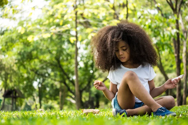 美丽的女孩坐在绿色的草在公园里 — 图库照片