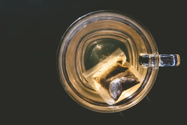 Стеклянная чашка чая с мешком на темном фоне — стоковое фото
