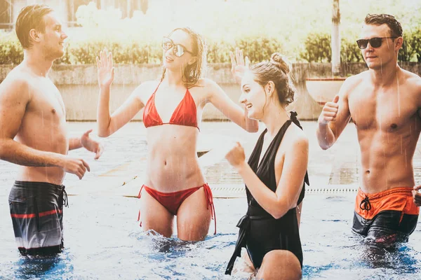 Group of friends enjoying vacation in summer time. Young people having fun dancing in swimming pool — Stock Photo, Image