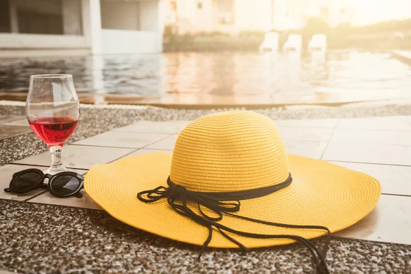 Sombrero, gafas de sol y copa de vino al lado de una piscina — Foto de Stock