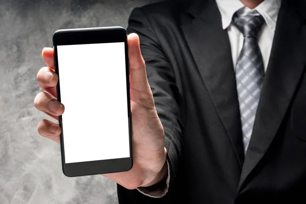 Nahaufnahme eines Mannes im schwarzen Anzug mit Smartphone und weißem Bildschirm auf grauem Grunge-Hintergrund — Stockfoto