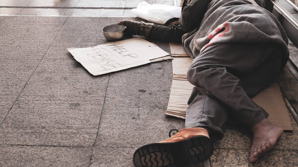 Homeless man sleeping on outdoor floor.