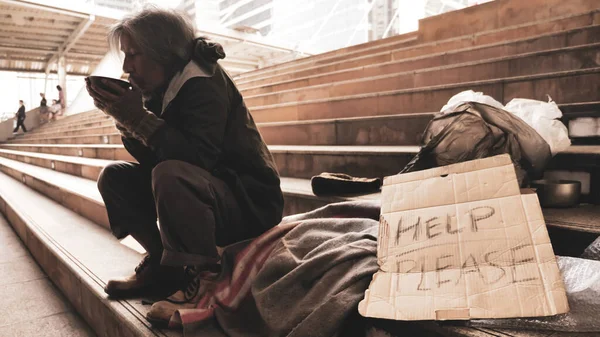 无家可归的男人坐在楼梯上吃着食物 — 图库照片