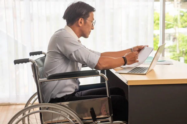 아시아 사업가가 휠체어에 사무실에서 서류를 확인하는 — 스톡 사진