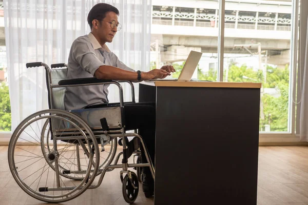 Azjatycki Biznesmen Siedzi Wózku Inwalidzkim Pisze Laptopie Biurze — Zdjęcie stockowe