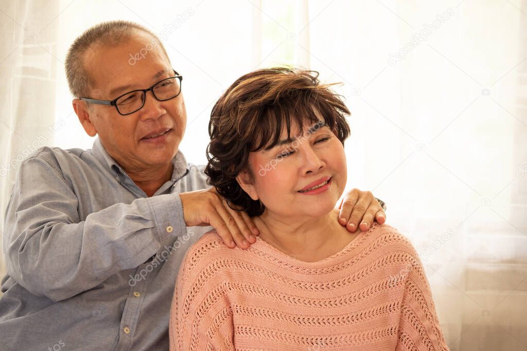 Happy asian husband massaging his wife shoulder in the house.