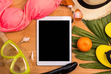 Tahta bir arka planda yaz dönemi için tablet ve aksesuarlar.