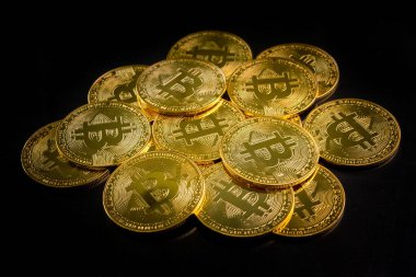 Siyah arkaplanda bitcoin sembolü olan altın paralar.