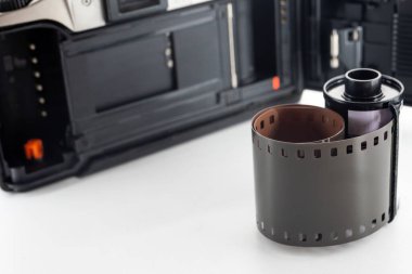 Tek lensli refleks kamera ve beyaz arka planda bir film rulosu.