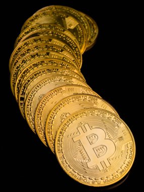 Siyah arkaplanda bitcoin sembolü olan altın paralar.