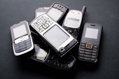 Siyah arka planda eski ve eski cep telefonları.
