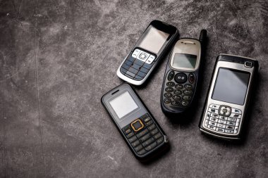 Grunge arka planında bir çok eski cep telefonu.