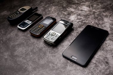 Pek çok eski cep telefonu ve grunge arka planda bir akıllı telefon..