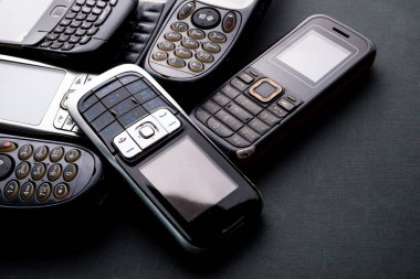 Siyah arka planda eski ve eski cep telefonları.