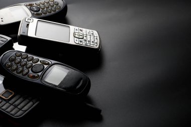 Siyah arka planda eski ve eski cep telefonları.