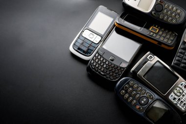 Siyah arka planda eski ve eski cep telefonları.
