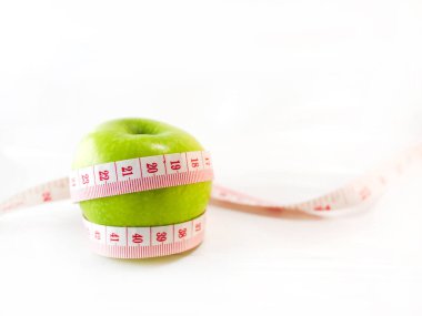 Ölçü bandıyla sarılmış yeşil elma