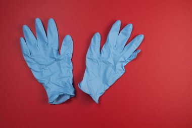 Mavi tıbbi lateks ya da kırmızı arka planda nitril eldiven. Yakın çekim, üst görünüm, metin için yer.