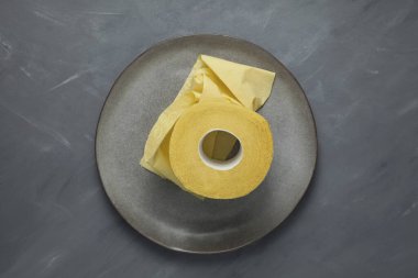 Tabaktaki sarı tuvalet kağıdı. Gri arka plan. Yakın çekim..