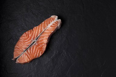 Siyah desenli arka planda çiğ somon bifteği. Boşluğu kopyala.