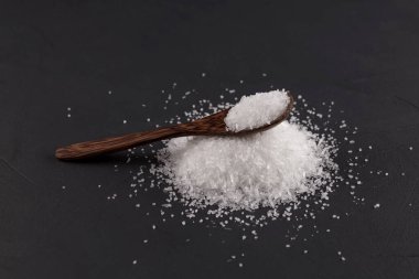 Koyu bir arka planda tahta bir kaşıkta monosodyum glutamat (Msg). E621 gıda takviyesi. Gıda deneyimini arttırmak için çeşninin tadına bak. Katkı maddesi gıda endüstrisinde kullanılıyor..