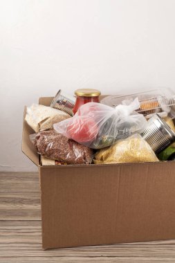 Farklı taze gıda ürünleriyle dolu karton bir kutu. Güvenli teslimat konsepti. Sosyal gıda bağışı. Güvensiz ev yemeği teslimatı. Seçici odaklanma. Metin için yer.