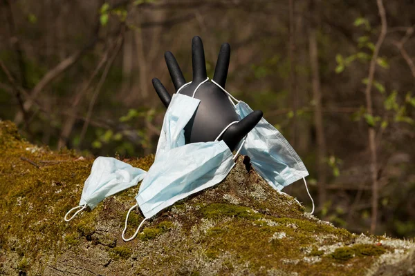 コロナウイルスパンデミックの発生による新しいタイプのゴミから概念保存自然 黒の医療用手袋ヘルプと使い捨てフェイスマスクの嘆願のシンボルとして — ストック写真