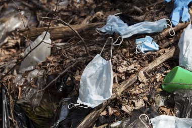 Kullanılmış yüz maskeleri ve eldivenler plastik kaplar ve plastik poşetlerle birlikte çöpe atılır. Coronavirüs salgınından kaynaklanan yeni atık türleri yüzünden doğanın kirlenmesi.