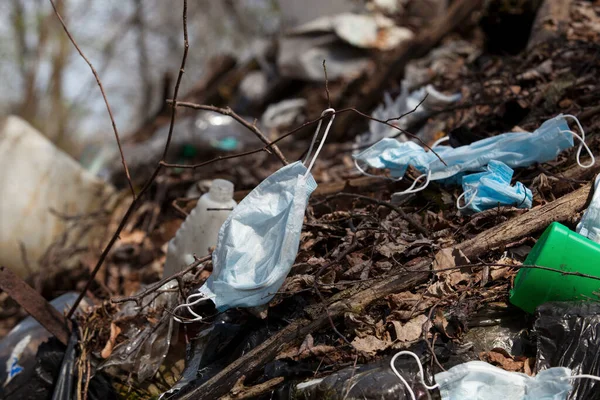 Environmental pollution with new types of waste resulting from the epidemic of coronavirus Covid-19. Used surgical face masks and medical gloves are thrown into the garbage dump.