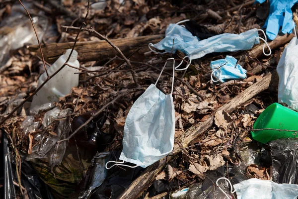 Used face masks and gloves are thrown into the garbage dump along with plastic containers and plastic bags. Pollution of nature by new types of waste resulting from the epidemic of coronavirus.