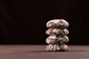 Çikolatalı kurabiyeler birbirlerinin üstünde yatıyorlar. Glütensiz ev yapımı tatlı. Koyu arkaplan, metin için yer.