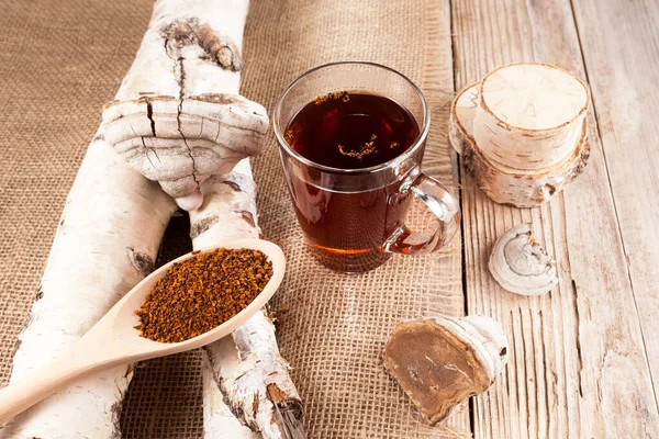 Ahşap bir arka planda cam bir fincanda Chaga mantarının kırsal bir biçimde bez bezi ile aşılanması. Sağlıklı içecek. Yukarıdan görüntüle.