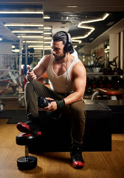 young muscular man exercising in gym and listening music