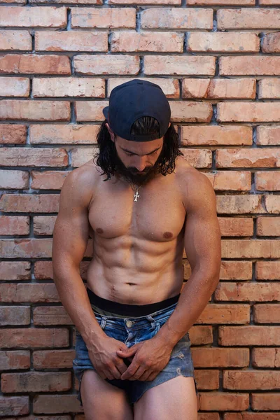 Jovem Homem Musculoso Jeans Curtos Posando Contra Parede Tijolo Homem — Fotografia de Stock