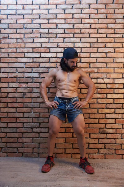 Kısa Pantolonlu Kaslı Genç Adam Tuğla Duvara Karşı Poz Veriyor — Stok fotoğraf
