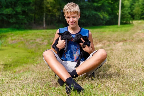 Happy teenager boy holding little black baby goats in the meadow — Stock Photo, Image