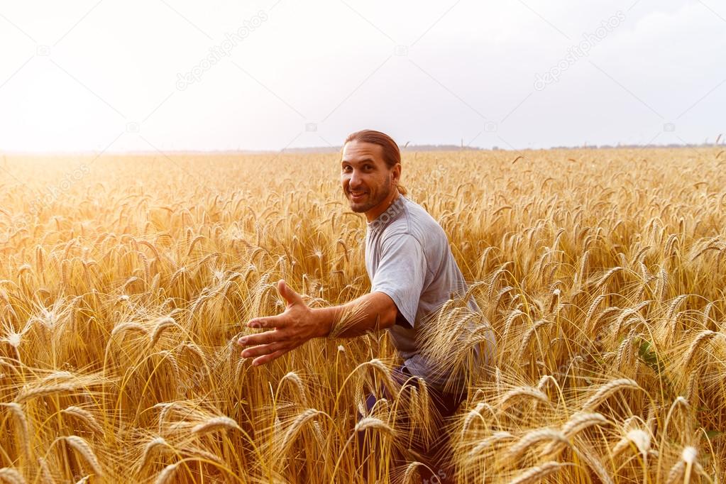 Funny man in field of wheat reaches out to the audience in the s