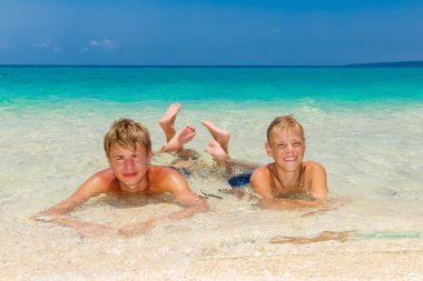 Mutlu genç çocuklar rahatlatıcı sahilde. Backg tropikal deniz