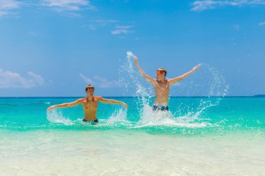 Mutlu genç çocuklar tropik sahilde eğleniyor. Yaz vacatio