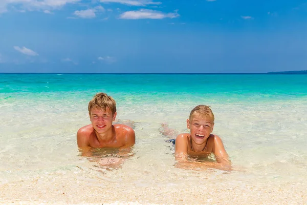 Happy teen boys relaxing on the beach. Tropical sea in the backg — Stock Photo, Image