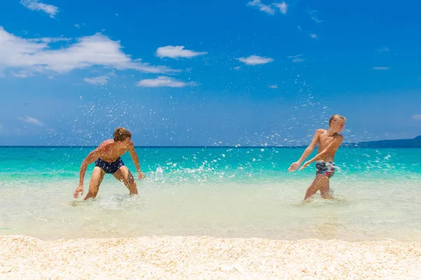 Fröhliche Teenie-Jungs, die Spaß am tropischen Strand haben. Sommerurlaub — Stockfoto