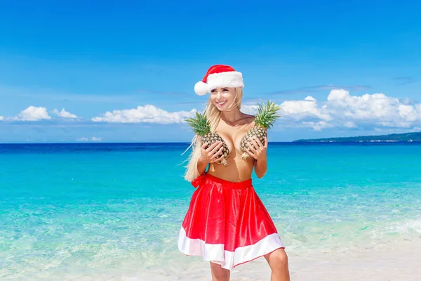 Beautiful cheerful blonde in Christmas hat and skirt holding a p — Stock Photo, Image