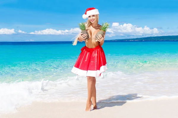 Beautiful cheerful blonde in Christmas hat and skirt holding a p — Stock Photo, Image