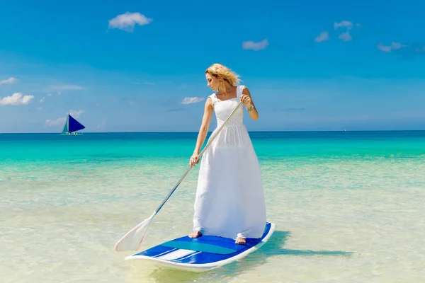 Glad vacker ung flicka i en vit klänning med paddel board på — Stockfoto