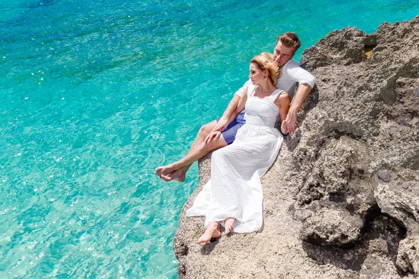 Happy groom and bride on the rock. Turquoise sea in the backgrou — Stock Photo, Image