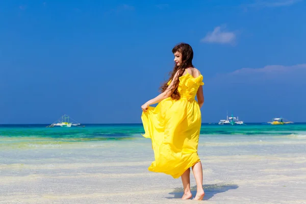 Beautiful brunette woman in yellow dress with her back to the vi — Stock Photo, Image