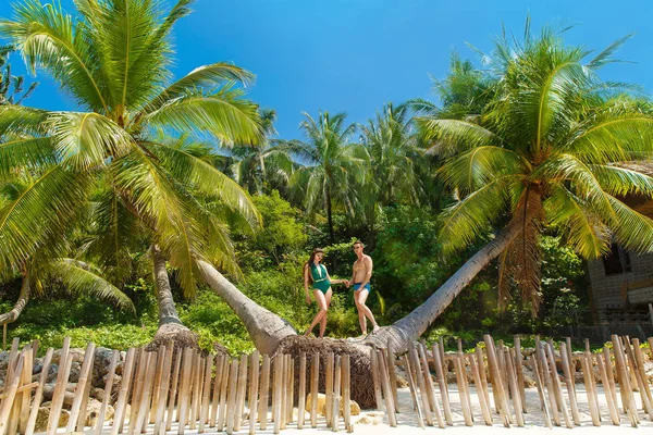 Unga älskande lyckliga paret under palmerna på en tropisk isl — Stockfoto