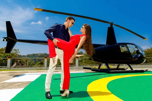 Ein junger eleganter Mann mit Sonnenbrille und eine Frau in Rot stehen daneben — Stockfoto