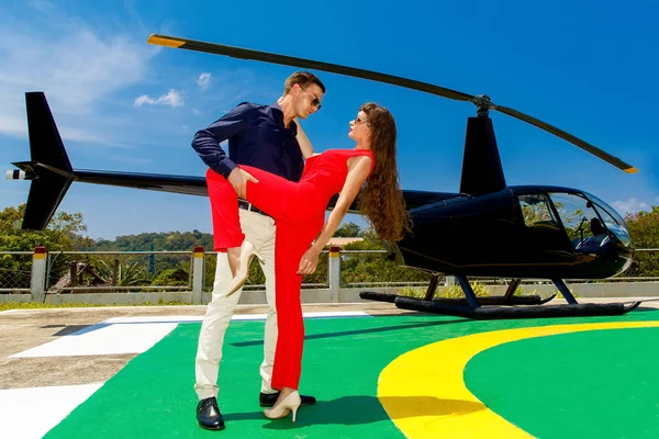 Joven hombre elegante en gafas de sol y una mujer en rojo de pie al lado —  Fotos de Stock